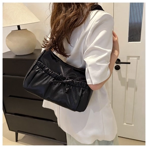 Détail du sac à épaule plissé noir avec nœud élégant et texture au fini satiné raffiné