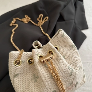 Elegant beige straw bucket bag with floral embroidery and gold chain strap for women