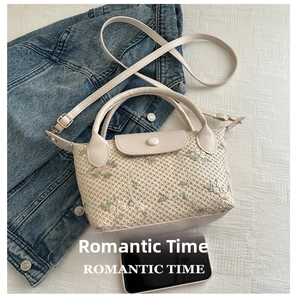 Detail of floral embroidery on a straw mini handbag with leather strap and top handles