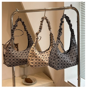 Three houndstooth pattern hobo bags with bow details hanging on a metal rack