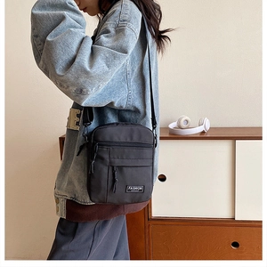 Detail of a black canvas crossbody bag with a FASHION label on a denim jacket model