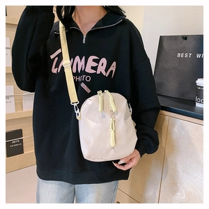 Detail of off-white crossbody bag with yellow strap and woven cord zipper pull