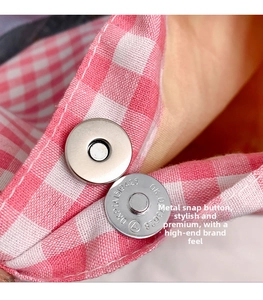 Detailed close-up of the silver magnetic clasp on a pink checkered canvas bucket bag
