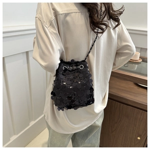 Close-up of black sequin bucket bag featuring silver eyelets and chain shoulder strap