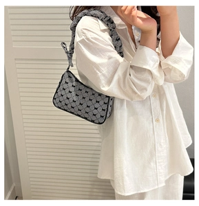 Detail of checkered shoulder bag with black bows and ruffled handle strap on model