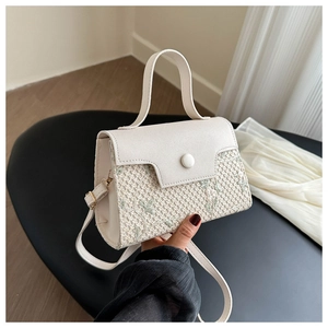 Dettaglio della borsa in paglia con ricamo floreale verde e finiture in pelle beige