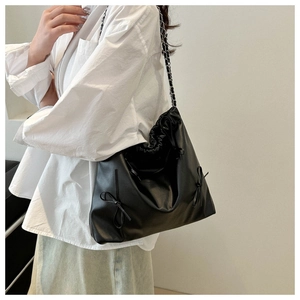 Minimalist black soft leather tote bag with drawstring closure and silver chain strap