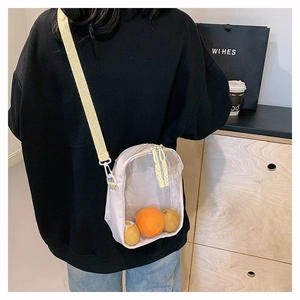 Detail of transparent PVC crossbody bag with white fabric strap and orange fruit inside