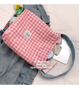 Detail of pink gingham tote bag interior with EMIS logo label and personal essentials