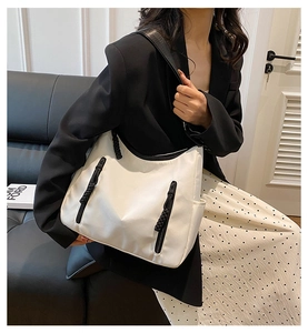 Detail of minimalist white tote bag with black rope zip pulls and wide shoulder strap