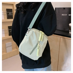 Detail of mint green nylon crossbody bag with woven zipper pull and wide strap