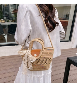 Detail of hand-woven straw bag featuring pearl buckle and delicate white lace bow