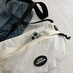 White nylon dumpling crossbody bag with adjustable black strap and front phone pocket