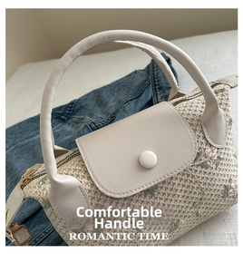 Detail of cream woven handbag featuring delicate floral embroidery and round button closure