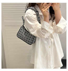 Detail of checkered shoulder bag with black bows and ruffled strap on white shirt