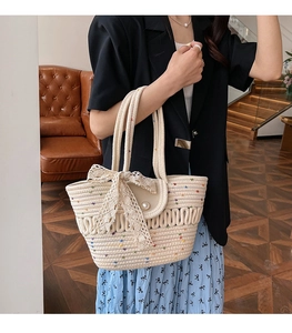 Detail of hand-woven straw tote bag with lace bow decoration and pearl button accent