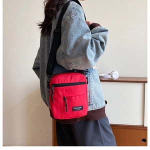 Red canvas crossbody bag worn by model, showing compact size and adjustable strap