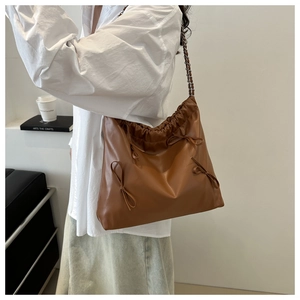 Brown PU leather tote bag with drawstring closure and bow details on a woven chain strap