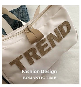 Detail of off-white nylon shoulder bag featuring TREND patch and durable metal zipper