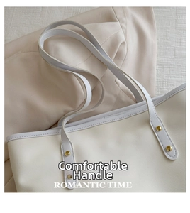 Dettaglio della borsa shopper bianca con manici rinforzati e rivetti dorati eleganti