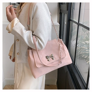 Close-up of pale pink crossbody bag with metal butterfly buckle and chain strap detailing