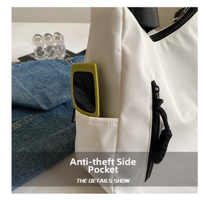 Detail showing white tote bag side anti-theft pocket with black strap and woven zipper