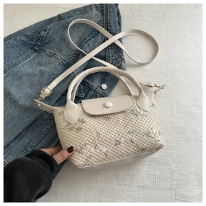 Detail of beige straw bag featuring pink floral embroidery and PU leather strap