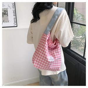 Close-up of pink checkered canvas tote bag with EMIS label and light blue wide strap