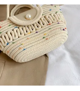 Detail of woven beige handbag featuring colorful speckles and elegant pearl closure button