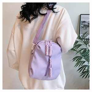 Detail of lavender nylon crossbody bag showing woven rope zippers and textured fabric