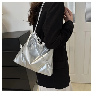 Close-up of metallic silver shoulder bag featuring drawstring closure and bow detail