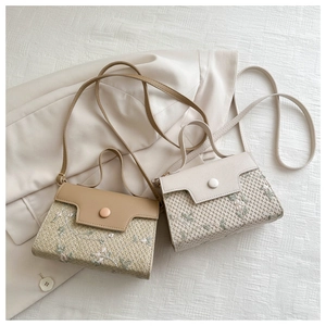 Detail of woven straw square bags with floral embroidery and leather flap closure