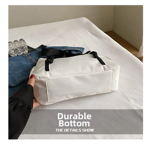 Detail view of the durable wear-resistant bottom on white nylon tote bag with black straps