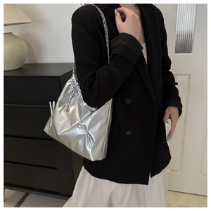 Detail view of silver bucket bag with chain strap and bow knot on female model