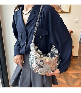 Detail of silver sequin crescent shoulder bag with metallic chain on fashion model