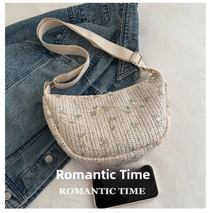 Detail of woven crescent crossbody bag with floral embroidery and canvas strap