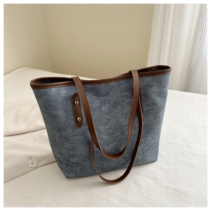 Dettaglio della borsa tote in tela grigio-blu con manici in pelle PU marrone e rivetti