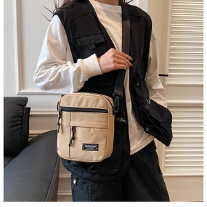 Close-up of khaki canvas crossbody bag featuring Fashion Instinct label and multi-pocket design
