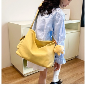 Detail of yellow canvas tote bag with fashion label and cute animal charm on side