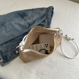 Handwoven straw tote bag with white rope straps on casual denim and beige bedding
