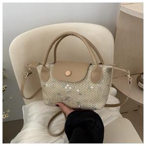 Detail of woven straw handbag with floral embroidery and khaki leather handle on chair