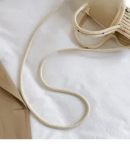 Detail of woven straw tote bag featuring a long shoulder strap and durable dual handles
