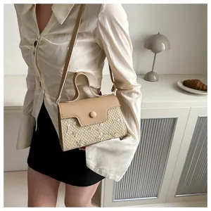 Detail of elegant straw woven handbag featuring floral embroidery and beige leather trim