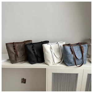 Dettaglio di quattro borse tote minimaliste in ecopelle in vari colori su un mobile bianco