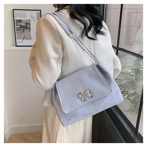 Detail of light blue PU leather shoulder bag with silver bow buckle and chain strap