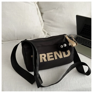 Detail of black nylon crossbody bag with TREND letter patch and fuzzy coal sprite charm