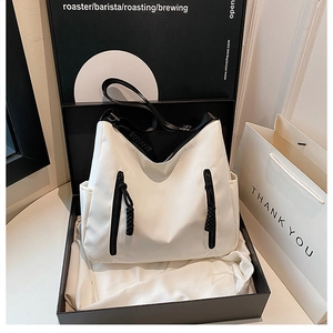 Detailed view of minimalist white tote bag with black zippers inside a gift box