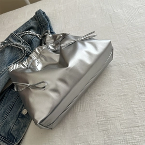 Silver metallic bow chain tote bag with pleated detail on white fabric background