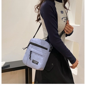 Close-up of lilac nylon crossbody phone bag with adjustable strap and front logo patch