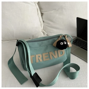 Detail of mint green oxford tote with TREND letter patch and fuzzy monster charm